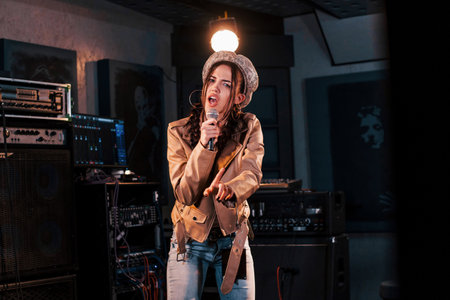 Young beautiful female performer rehearsing in a recording studioの写真素材