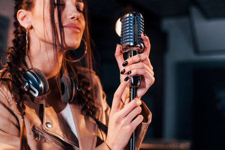 Young beautiful female singer rehearsing in a recording studioの写真素材