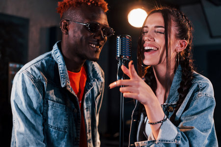 Two multi ethnic friends have a vocal practice in the studio togetherの写真素材