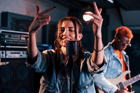 Guy plays guitar, girl sings. African american man with white girl rehearsing in the studio togetherの写真素材