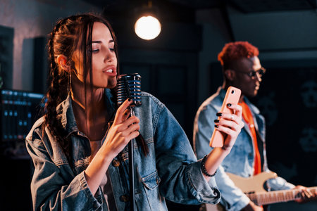 Guy plays guitar, girl sings. African american man with white girl rehearsing in the studio togetherの写真素材