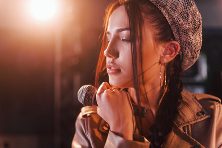 Young beautiful female performer rehearsing in a recording studioの写真素材