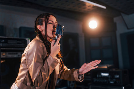 Young beautiful female performer sings and rehearsing in a recording studioの写真素材