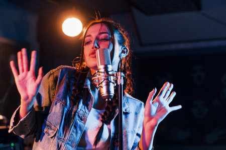 Young beautiful female performer sings and rehearsing in a recording studioの写真素材