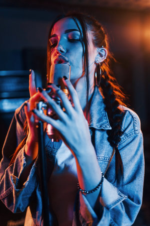 Young beautiful female singer rehearsing in a recording studioの写真素材