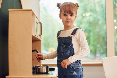 Little girl in casual clothes have fun by playing with toys on the kitchenの写真素材