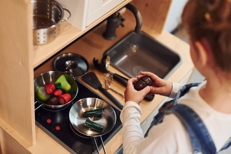 Little girl in casual clothes have fun by playing with toys on the kitchenの写真素材