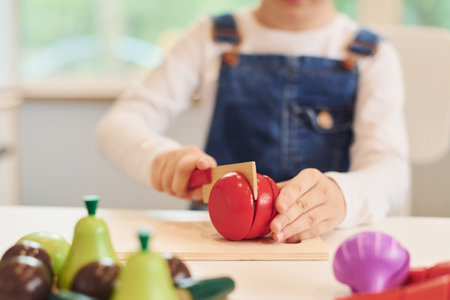 Close up view of little girl in casual clothes that have fun by playing with toys on the kitchenの写真素材