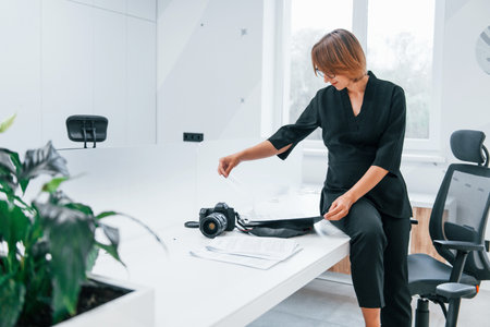 Woman in black formal clothes and with camera in the officeの写真素材