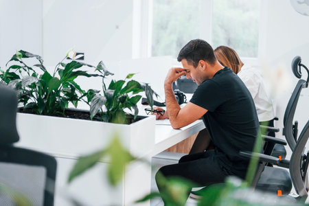 Tired man and woman sitting by the table and working in the officeの写真素材