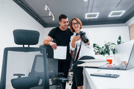 Man in black clothes watching photos on the females photographer cameraの写真素材