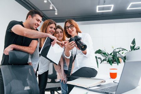 Group of business people in formal clothes indoors in the office looking at photos on the cameraの写真素材