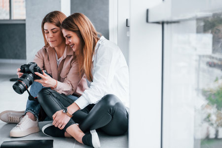 Two women sitting indoors together and looks at photos on the cameraの写真素材