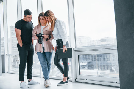 Group of people standing indoors together and looks at photos on cameraの写真素材