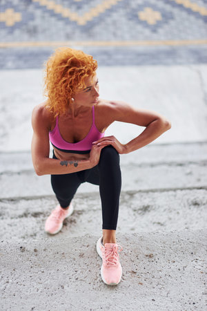 Young european redhead woman in sportive clothes doing squats outdoorsの写真素材