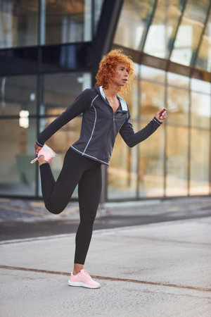 Young european redhead woman in sportive clothes doing exercises outdoorsの写真素材