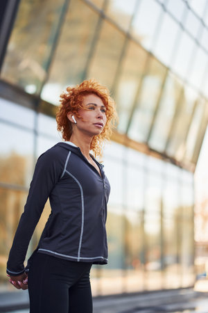 Young european redhead woman in sportive clothes doing exercises outdoorsの写真素材