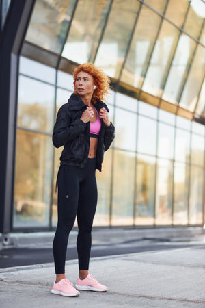 Young european redhead woman in sportive clothes standing outdoorsの写真素材