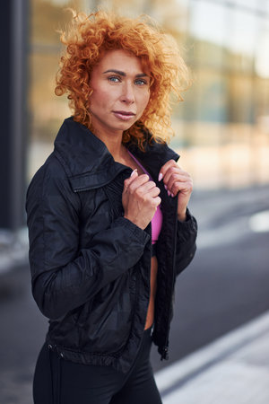 Young european redhead woman in sportive clothes standing outdoorsの写真素材