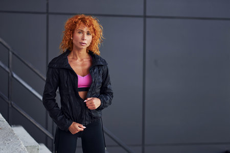 Young european redhead woman in sportive clothes standing outdoors