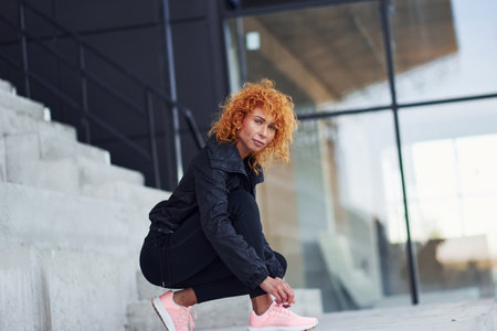 Young european redhead woman in sportive clothes wearing shoes outdoorsの写真素材