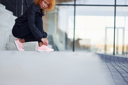 Young european redhead woman in sportive clothes wearing shoes outdoorsの写真素材