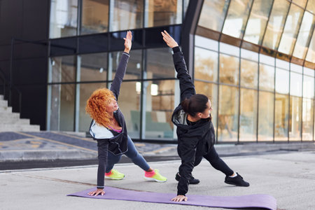 Doing push ups. Two female friends with sportive bodies have fitness day outdoorsの写真素材