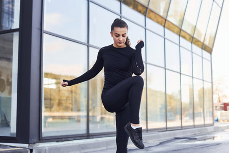 Young brunette in sportive clothes have fitness day outdoors in the cityの写真素材