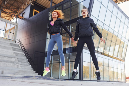 Two female friends with sportive bodies have fitness day outdoors