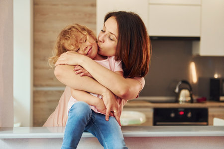 On the kitchen. Young mother with her little daughter in casual clothes together indoors at homeの写真素材