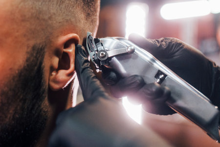 Close up view of young bearded man that sitting and getting haircut in barber shopの写真素材