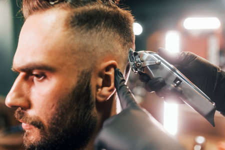 Close up view of young bearded man that sitting and getting haircut in barber shopの写真素材