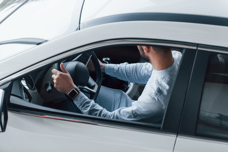 Young handsome man in formal clothes sitting in brand new automobileの写真素材