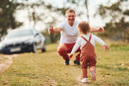 Father in casual clothes have walk and fun with daughter outdoors near forestの写真素材
