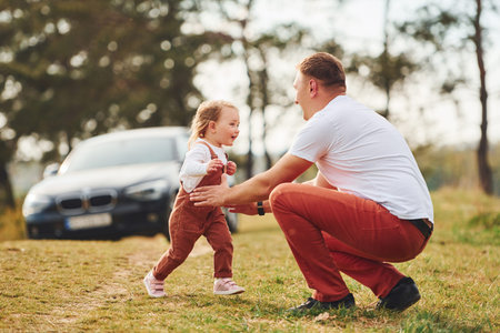 Father in casual clothes have walk and fun with daughter outdoors near forestの写真素材