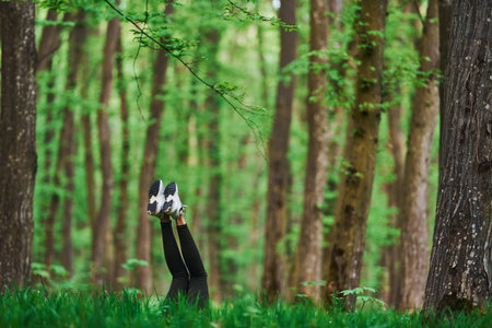 Legs of woman that have a rest and lying down on ground in forestの写真素材