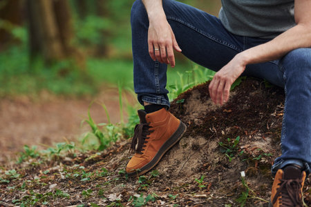Close up view of mans legs on the rock in forest. Traveler have a walkの写真素材
