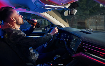 Black and red police lights. Dont drink and drive. Side view of handsome unshaved man in fashionable clothes inside his automobileの写真素材