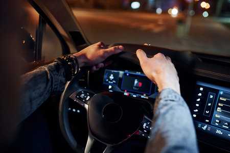 Handsome unshaved man in fashionable clothes riding his automobile