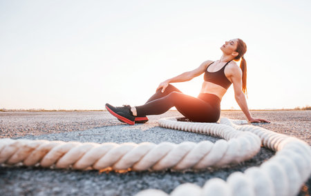 Woman in sportswear sitting with knots on the road at evening timeの写真素材