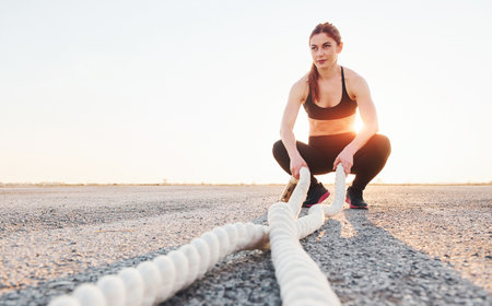 Woman in sportswear sitting with knots on the road at evening timeの写真素材
