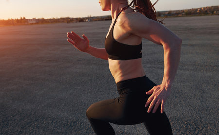 Woman in sportswear running on the road at evening timeの写真素材