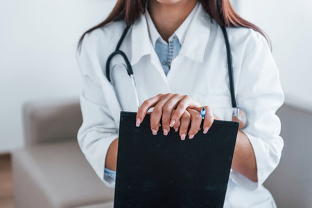 With notepad. Young nurse indoors in modern clinic. Conception of healthcareの写真素材