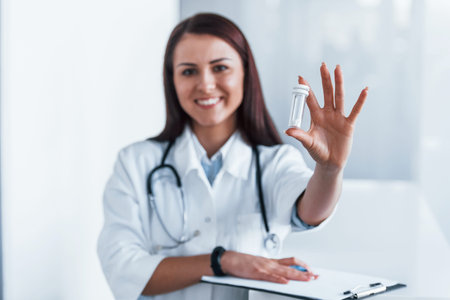Holding drugs in hand. Young nurse indoors in modern clinic. Conception of healthcareの写真素材
