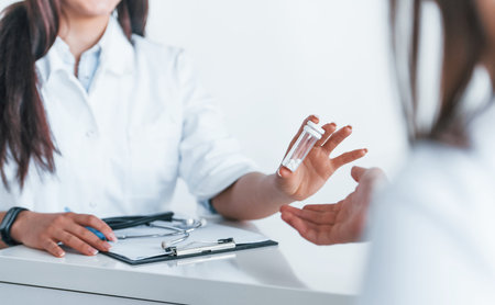Doctor gives drugs to patient. Young woman have a visit with female doctor in modern clinicの写真素材