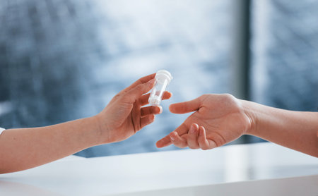 Doctor gives drugs to patient. Young woman have a visit with female doctor in modern clinic