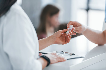 Doctor gives drugs to patient. Young woman have a visit with female doctor in modern clinicの写真素材