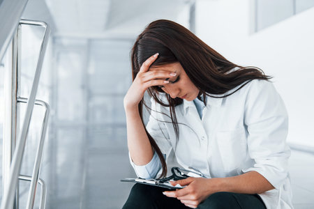 Young nurse reading documents indoors in modern clinic. Conception of healthcareの写真素材