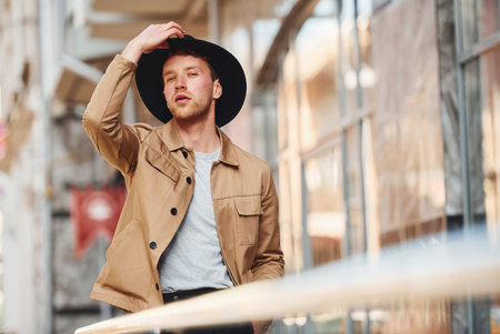 Elegant young man in black hat and formal classy clothes outdoors in the cityの写真素材