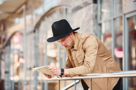 Elegant young man in formal classy clothes outdoors in the city reading newspaperの写真素材